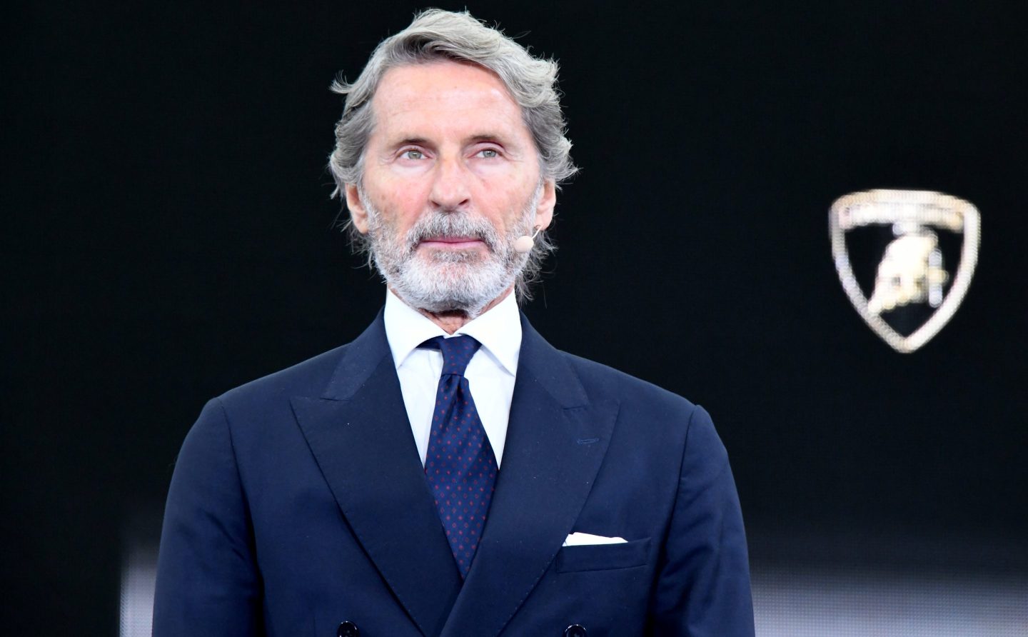 Stephan Winkelmann, wearing a dark suit, stands in front of a black background with the Lamborghini logo.