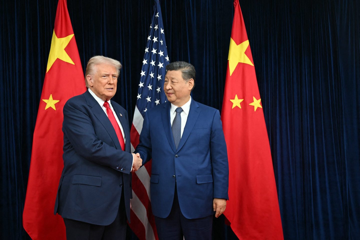 US President Donald Trump (L) and China's President Xi Jinping shake hands as they arrive for talks at the Gimhae Air Base, located next to the Gimhae International Airport in Busan on October 30, 2025.