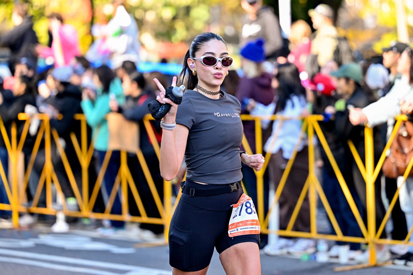 A woman holds up a peace sign as she runs in the New York City Marathon.