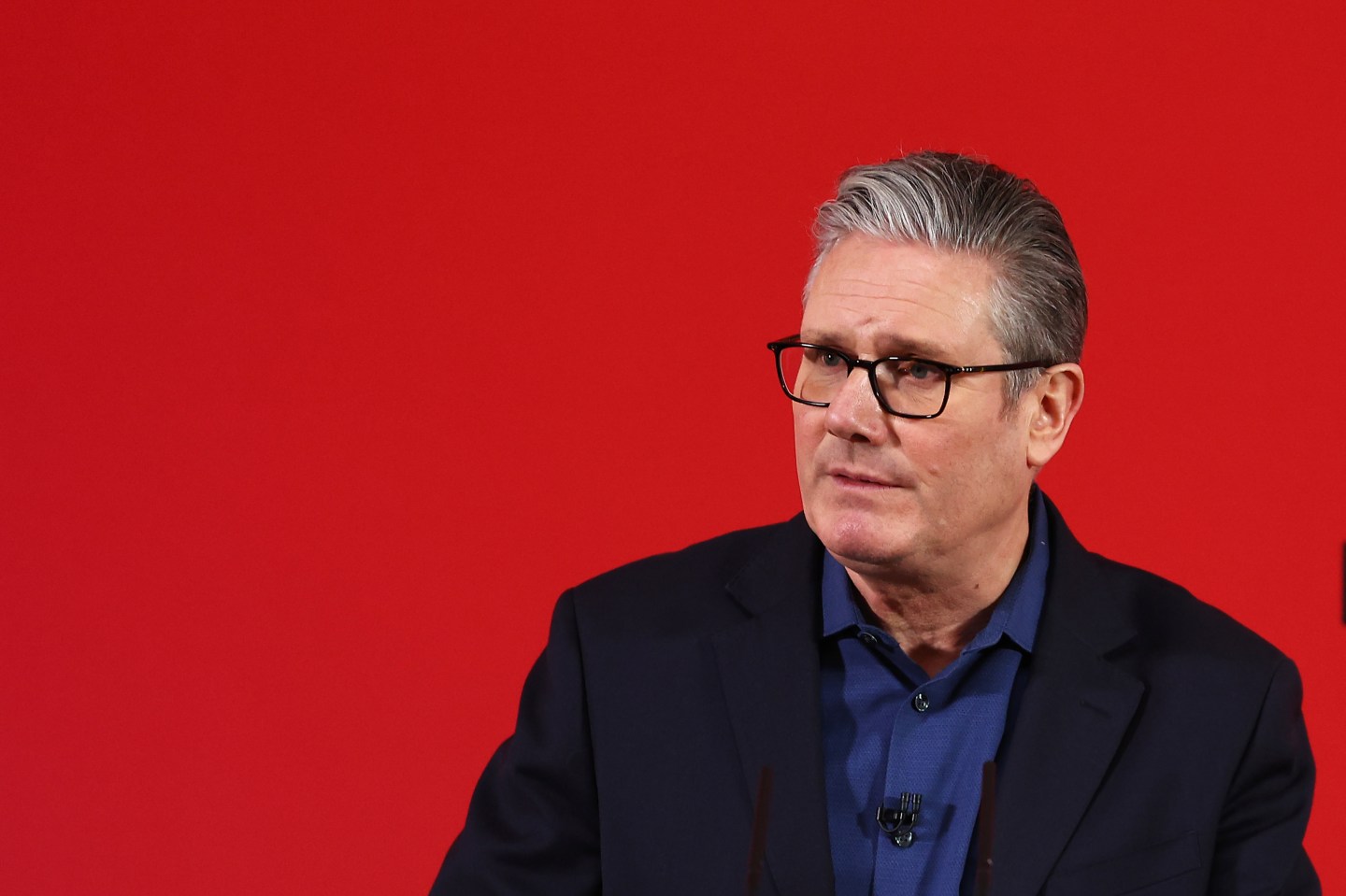 Starmer speaks in front of a red background