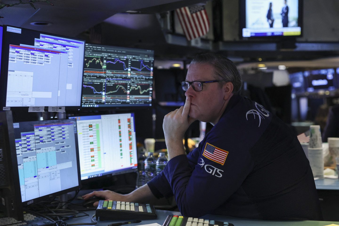 A trader at the New York Stock Exchange looks at screens while appearing concerned