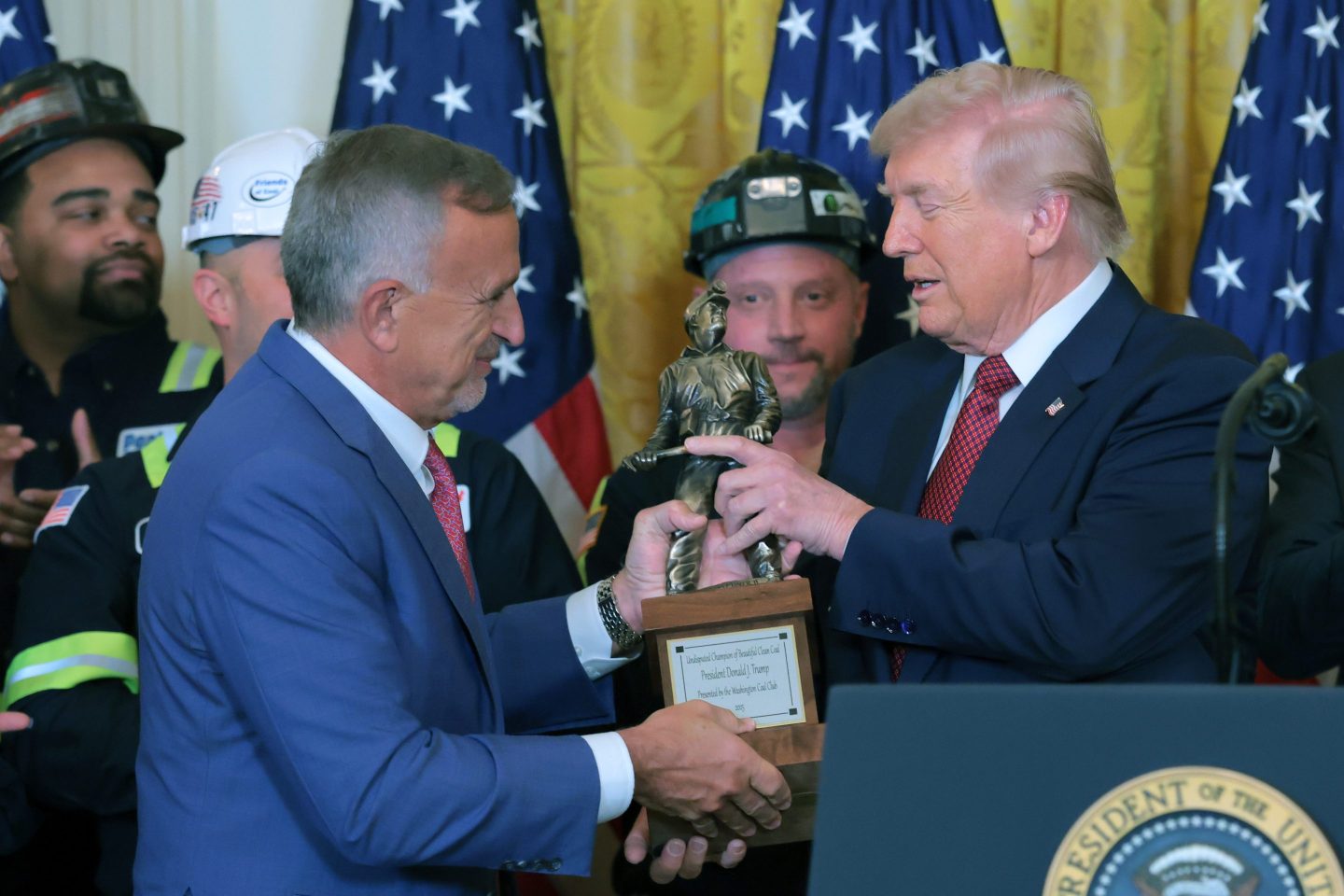 The CEO of coal producer Peabody Energy, Jim Grech, left, hands a trophy to U.S. President Donald Trump during an event on the use of coal in the East Room of the White House on Feb. 11, 2026 in Washington, DC. The lobbyist group, the Washington Coal Club, awarded Trump the inaugural "Undisputed Champion of Coal" award. Trump also is signing an executive order directing the Defense Department to buy electricity from coal-fired power plants. (Photo by Anna Moneymaker/Getty Images)