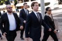Zuckerberg walks flanked by a man and a woman wearing Meta Ray-Ban glasses.