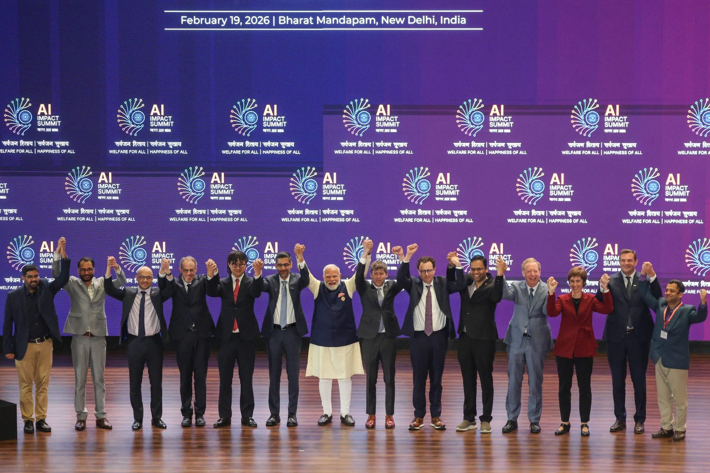 Tech leaders hold hands on stage at India's AI Impact Summit.