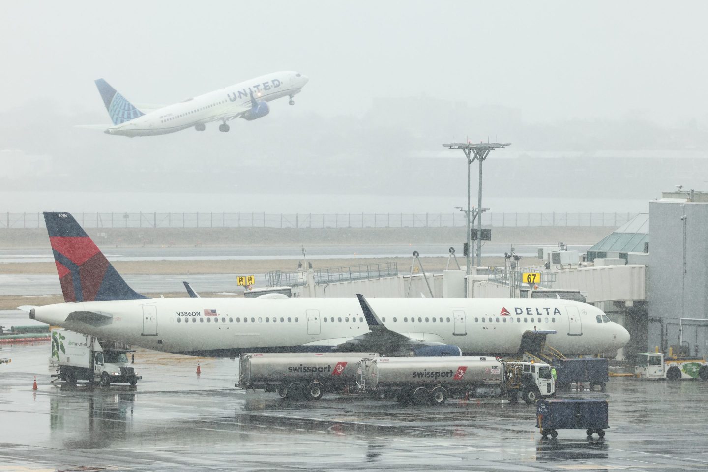 An Airbus A321 Delta Airlines passenger aircraft is seen at gate while a Boeing 737 MAX 8 United Airlines passenger aircraft takes off at LaGuardia Airport in New York on February 22, 2026. A fast-developing storm is threatening to pummel the US East Coast with a foot or more of snow beginning Sunday, bringing Mother Nature's wrath to a region that only just dug out from a previous winter wallop. Meteorologists issued blizzard warnings for New York and parts of at least six states, warning Saturday that heavy snow and gale-force winds are forecast to slam all major cities along the densely populated Interstate 95 northeast corridor, including Philadelphia, Boston and even Washington further south. (Photo by CHARLY TRIBALLEAU / AFP via Getty Images)