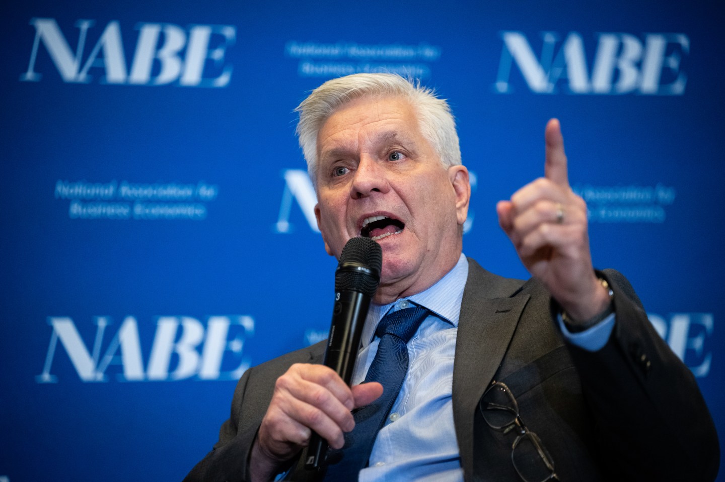 Waller speaks and points with a microphone in his hand.