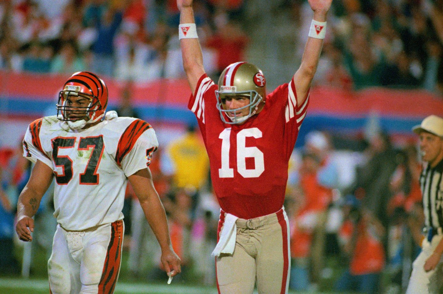 (Original Caption) 49ers quarterback Joe Montana raises his arm in celebration after throwing a touchdown pass to Jerry Rice in the fourth quarter. Bengal Sam Kennedy looks on.