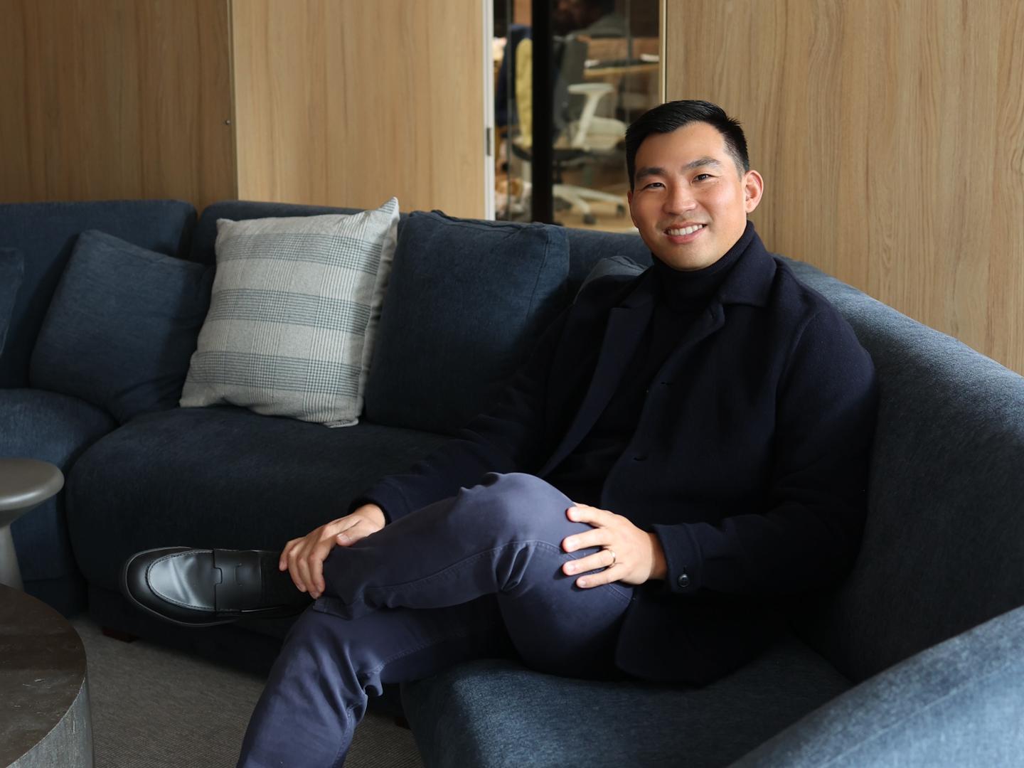 John Zhao smiles and crosses his legs