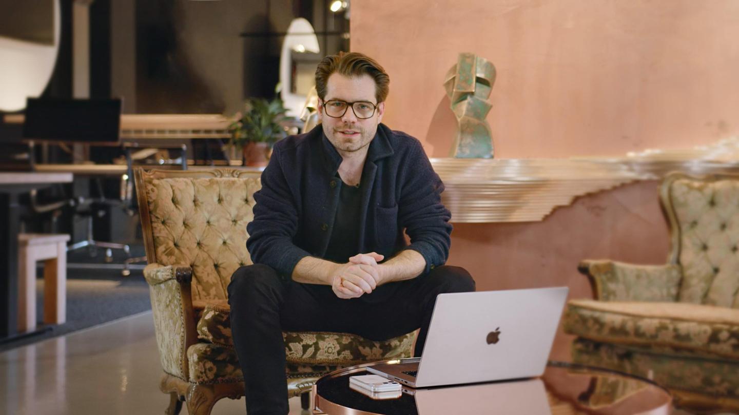 Interloom cofounder and CEO Fabian Jakobi sitting on a chair leaning forward towards on low coffee table on which sits a laptop.