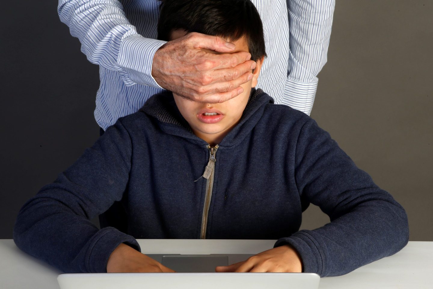kid on laptop with parent blindfolding them