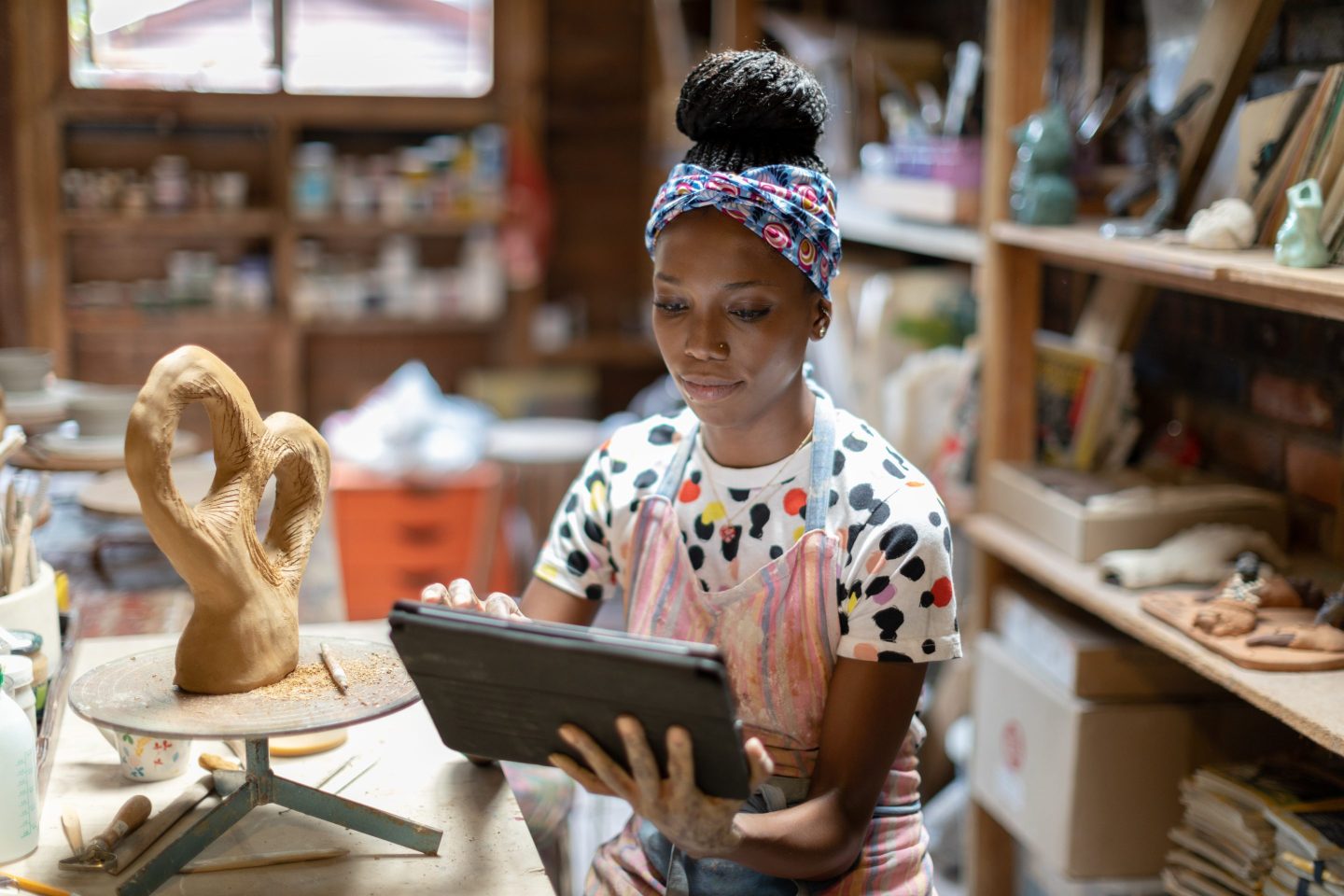 Female sculptor using a digital tablet in her art studio