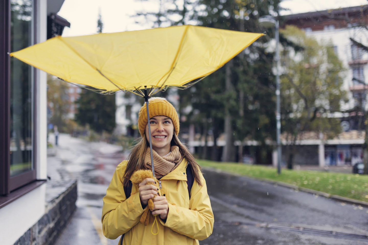 Woman holding a yellow umbrella that has become inverted in the wind.