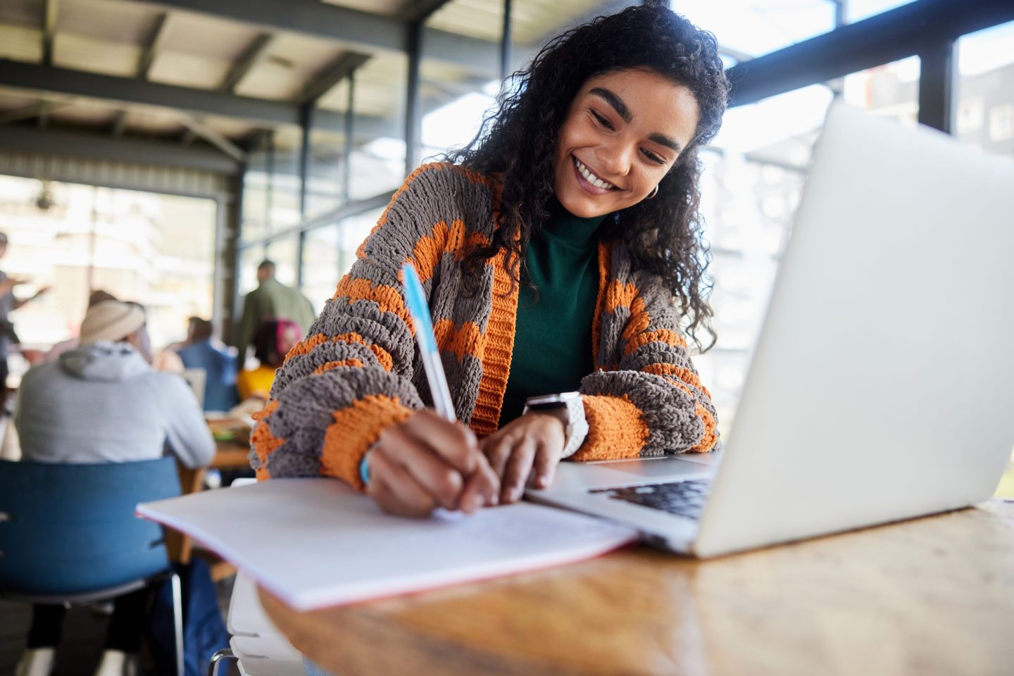 Young female college student smiling while doing homework