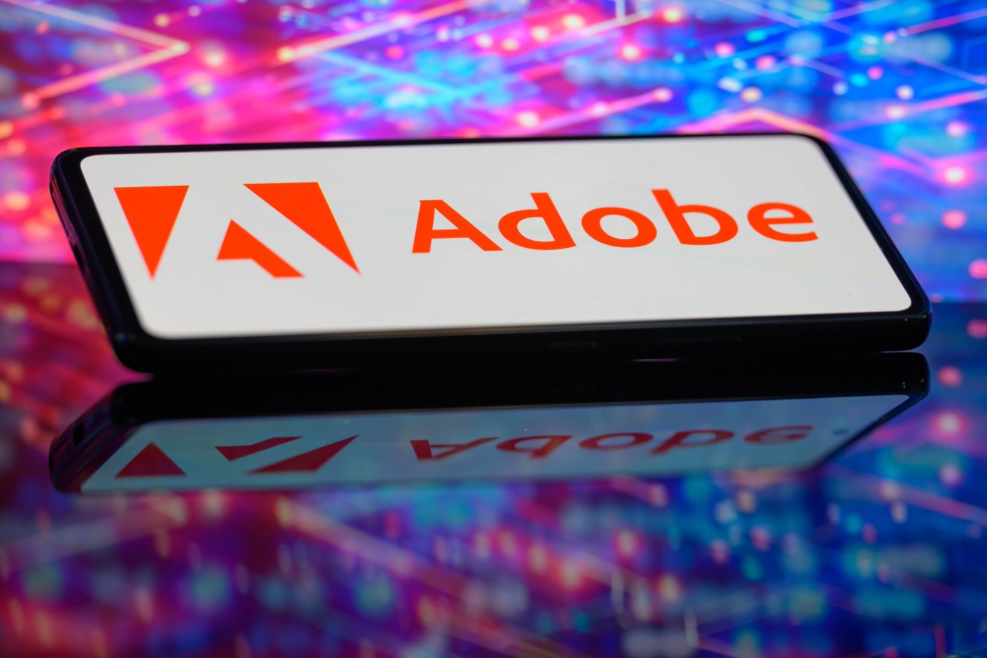 The Adobe logo is being displayed on a smartphone in this photo illustration.