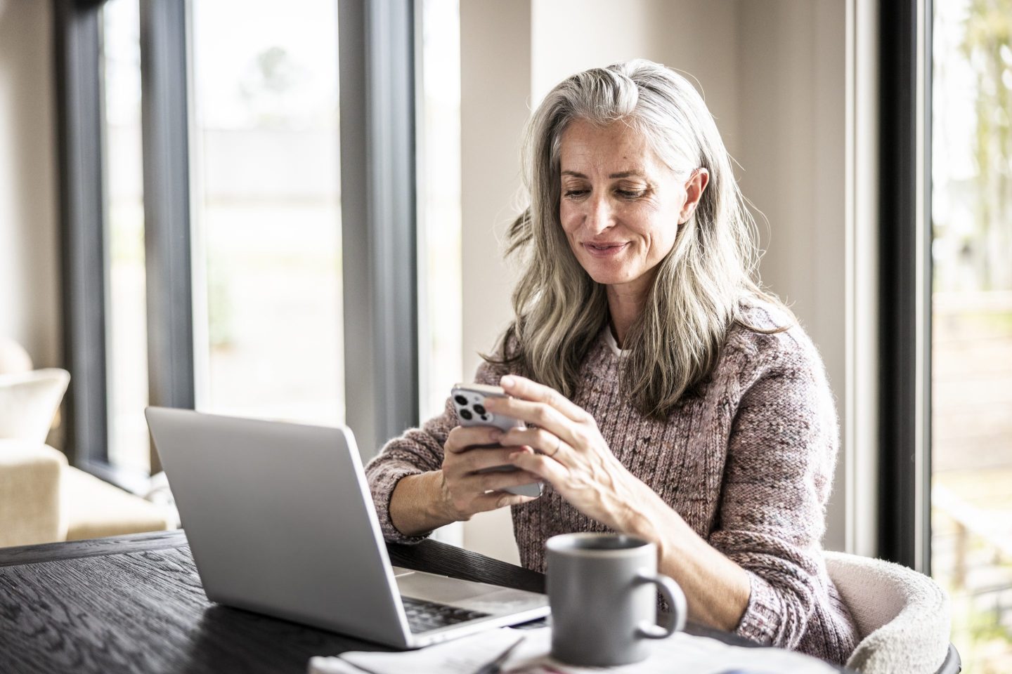 Woman using smartphone and laptop at home