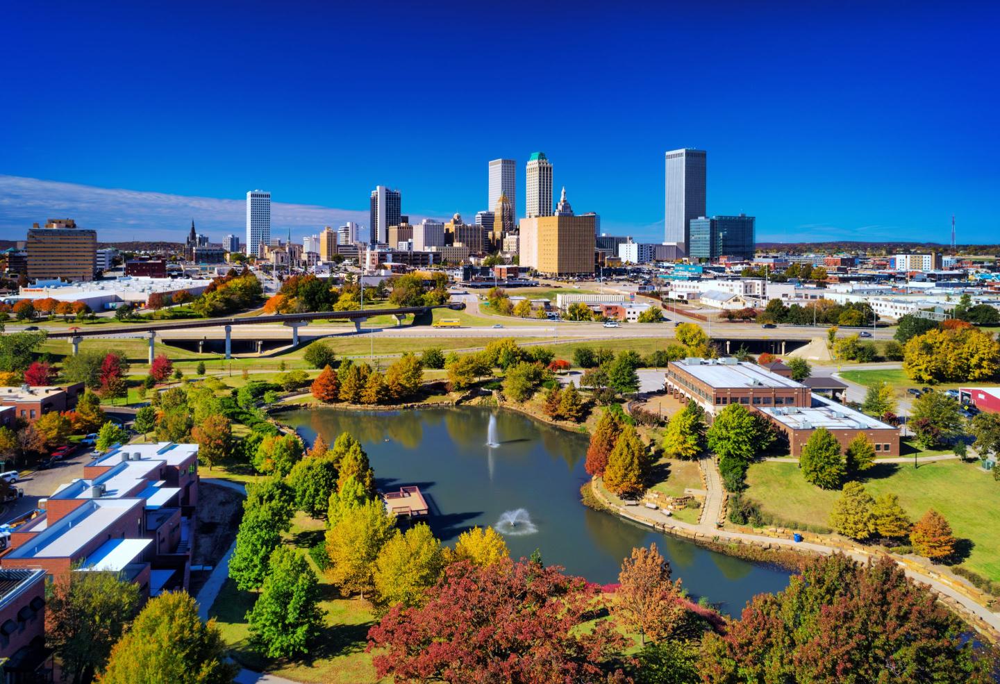 Downtown Tulsa skyline aerial view with a park and lake in the foreground, during autumn.