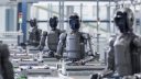 Faceless humanoid robots working on some kind of assembly line.