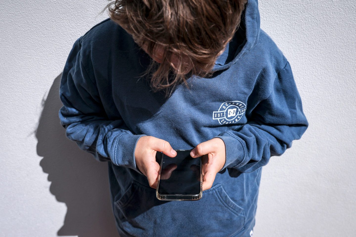 This photo taken on October 24, 2025 shows a 14-year-old boy posing at his home near Gosford as he looks at social media on his mobile phone. Tech giants Meta and TikTok said on October 28 they will obey Australia's under-16 social media ban but warned the landmark laws could prove difficult to enforce. Australia will from December 10 force social media platforms such as Facebook, Instagram and TikTok to remove users under the age of 16. (Photo by David GRAY / AFP via Getty Images)