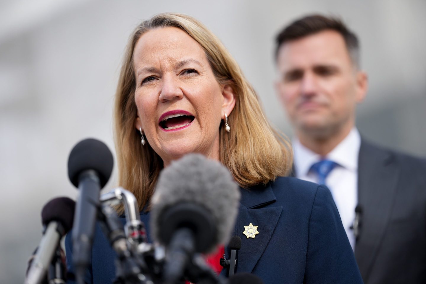 Mayes speaks at a podium.