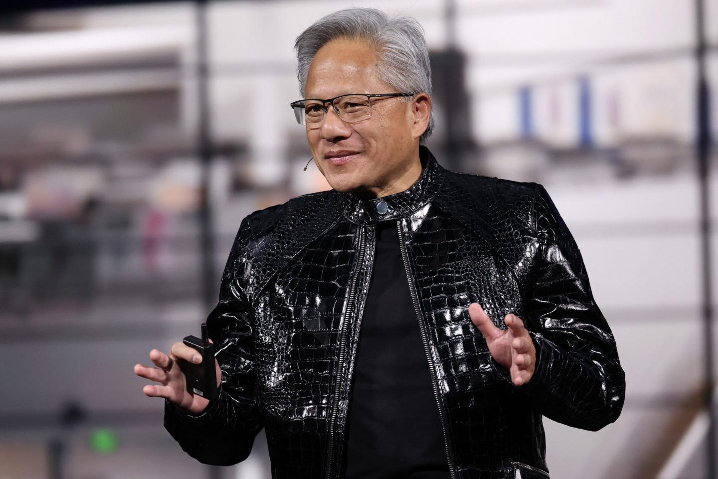 Man in a black leather jacket gesturing with his hands.