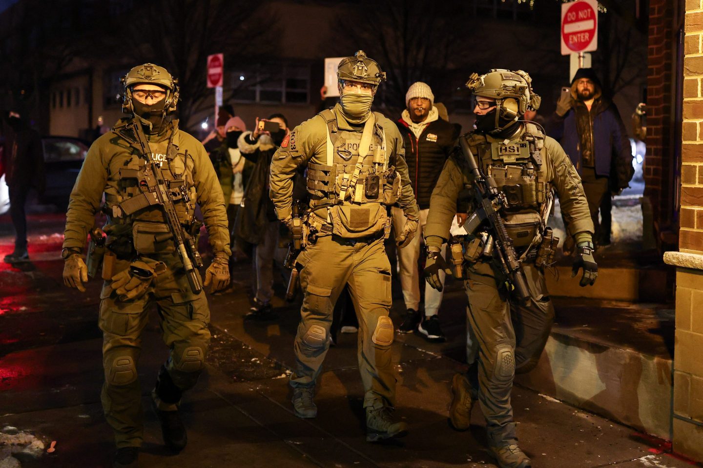 TOPSHOT - Federal agents with Homeland Security Investigations (HSI) depart the area outside a residential building after detaining a protestor in Minneapolis, Minnesota, on February 5, 2026. US President Donald Trump suggested on February 4 that a "softer touch" may be needed on immigration, as his administration said 700 federal officers would be pulled from Minnesota but that mass deportations would not stop. The fatal shootings of two protesters by federal officers in Minneapolis last month sparked widespread outrage in the United States and calls for an end to immigration raids in the Midwestern city, but Trump's administration has been reluctant to shift course. (Photo by CHARLY TRIBALLEAU / AFP via Getty Images)