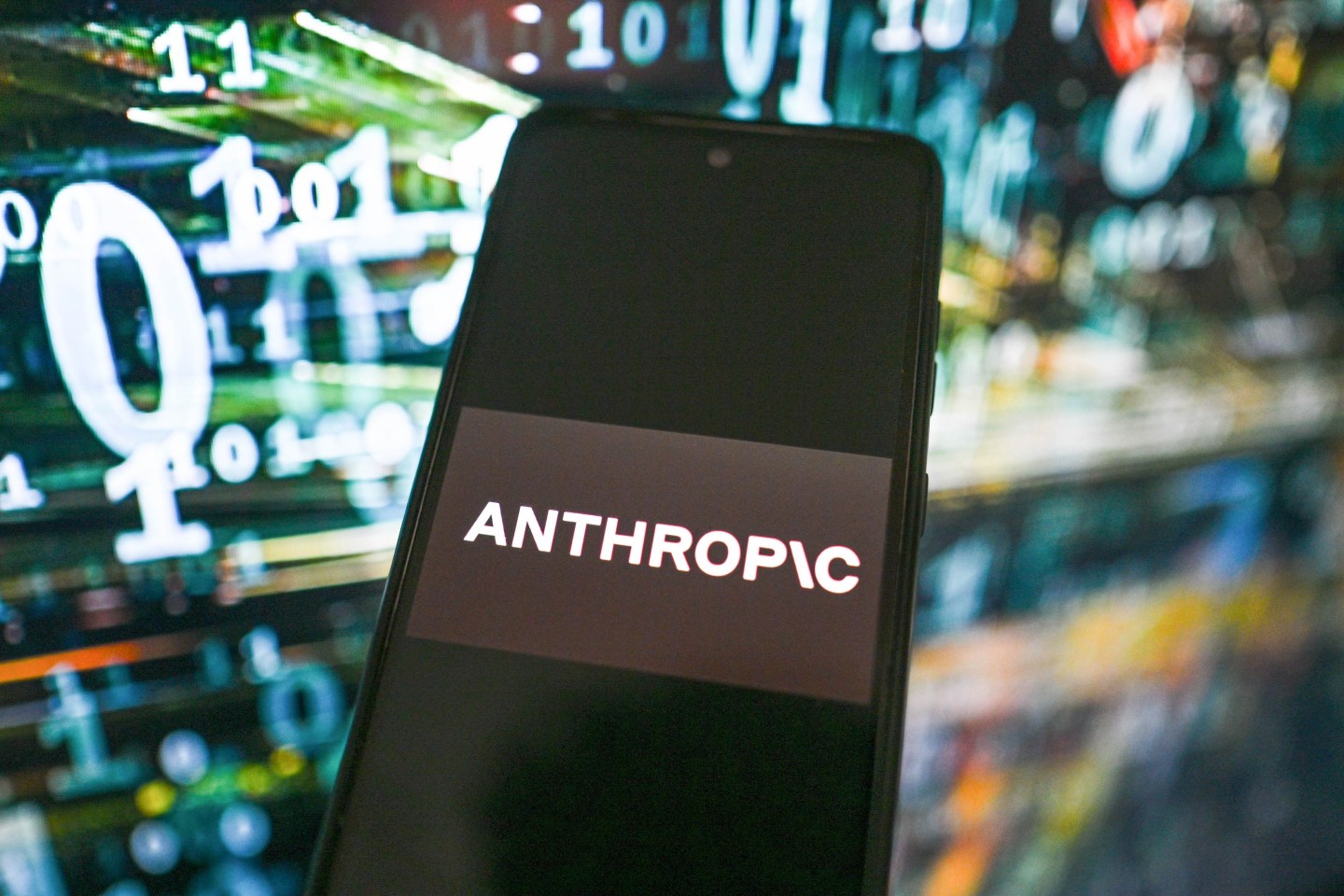 In this photo illustration, an Anthropic logo is seen displayed on a smartphone with stock market percentages on the background.
