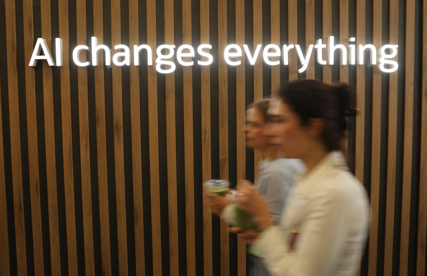 Women walk past a sign