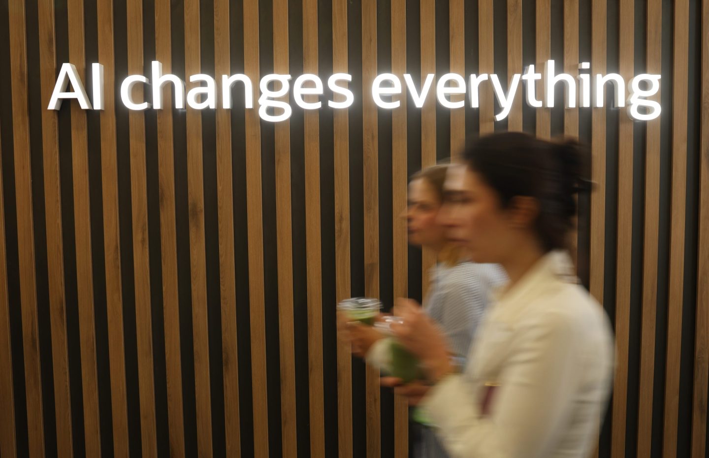 Women walk past a sign