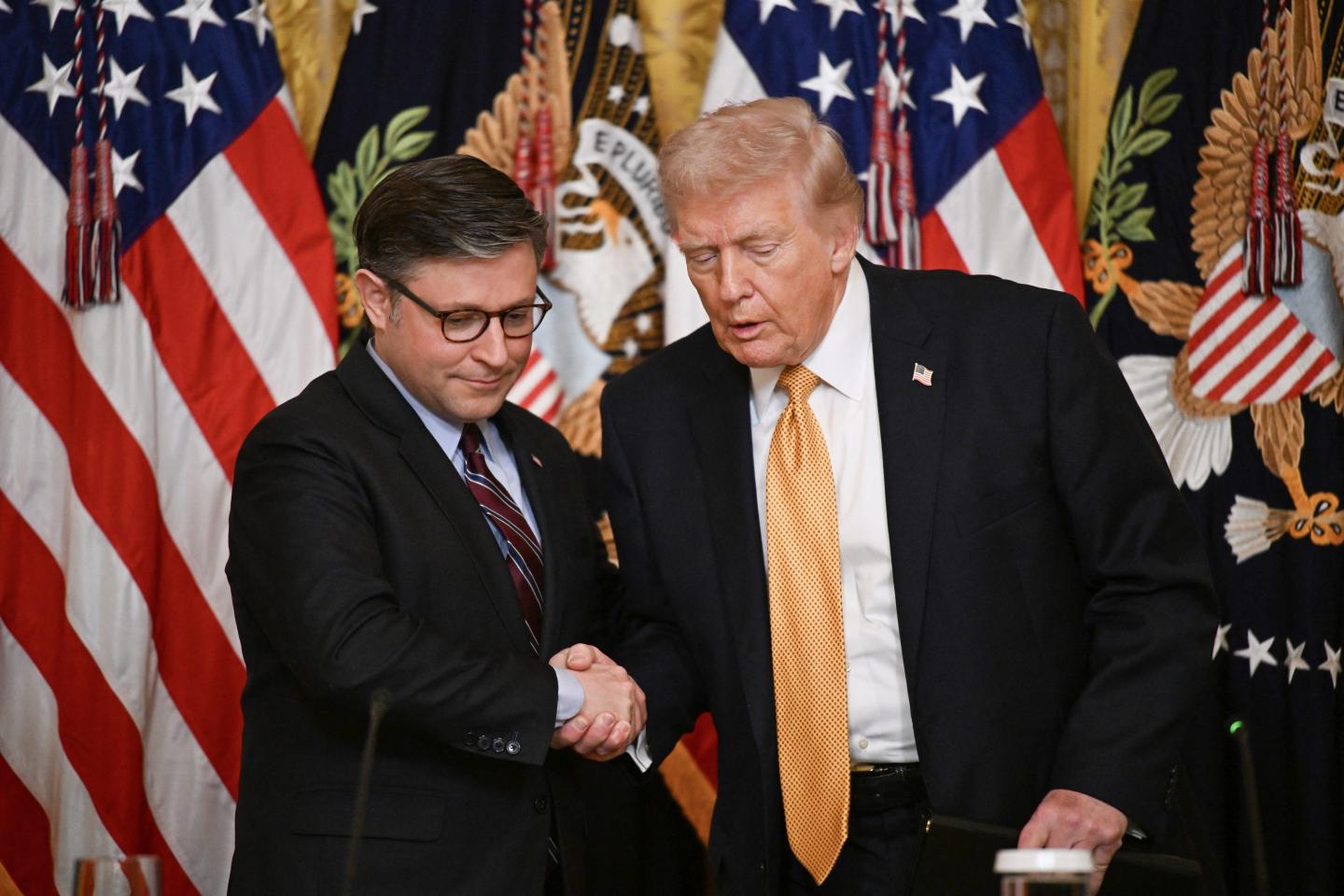 President Donald Trump (right) shakes hands with Speaker of the House Mike Johnson in the East Room of the White House on March 16, 2026, in Washington, D.C.