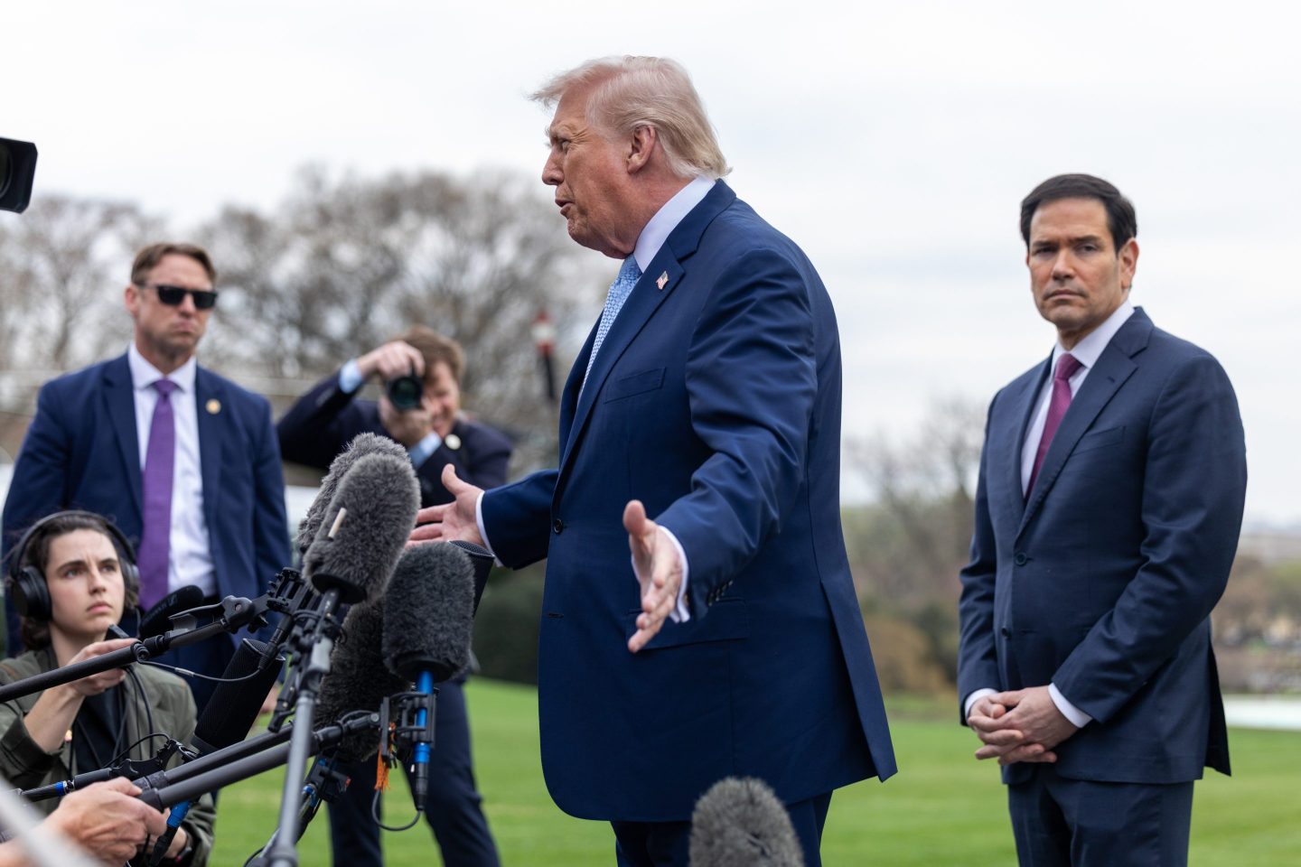 US President Donald Trump, left, and Marco Rubio, US secretary of state, speak to members of the media on the South Lawn of the White House before boarding Marine One in Washington, DC, US, on Friday, March 20, 2026. US officials said the White House is sending more than 2,000 additional Marines to the Middle East as it weighs a plan to seize Iran's Kharg Island oil export hub, a ground operation that would carry huge risks for President Donald Trump.