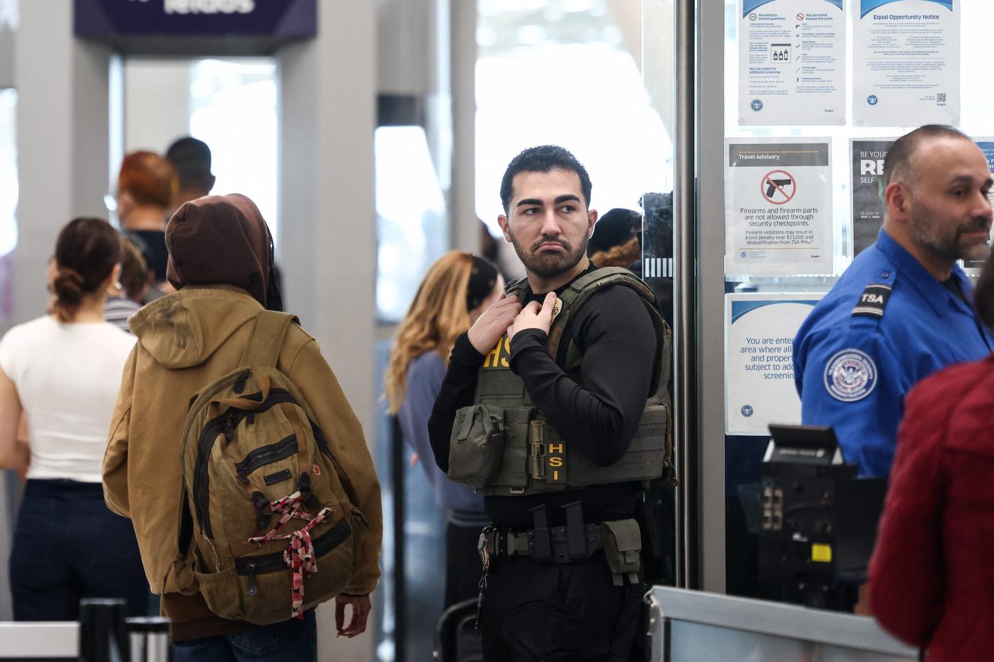 A Homeland Security Investigations federal agent stands at an airport security checkpoint.