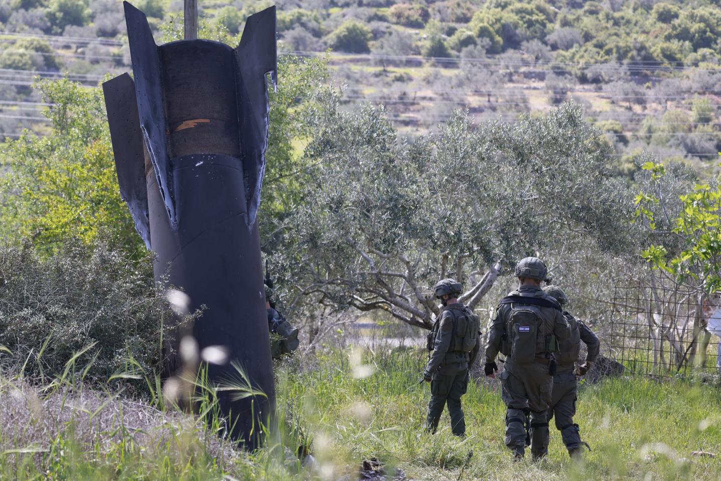Israeli soldiers examine the remnants of an Iranian missile that landed in the Israeli-occupied West Bank village of Hares, March 24, 2026. 