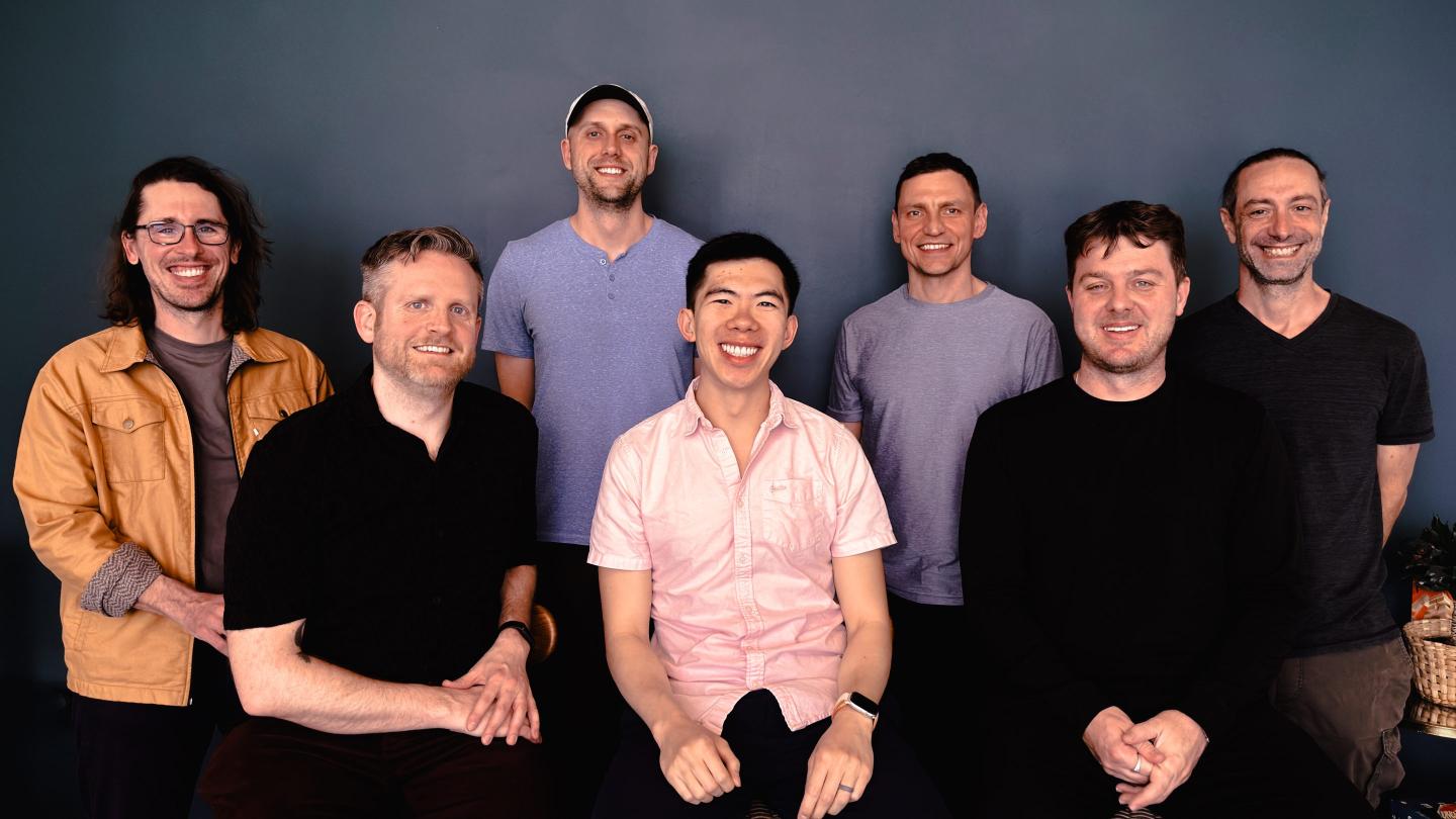 startup team smiles in front of camera