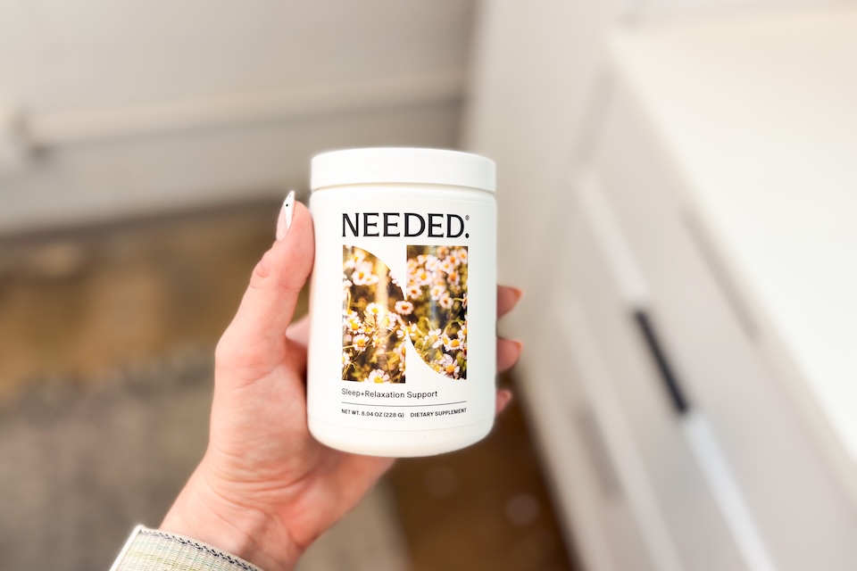 A hand holding a container of Needed Sleep and Relaxation Support.