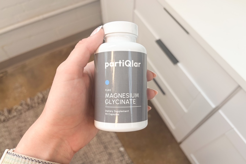 A hand holding a bottle of partiQlar Magnesium Glycinate.