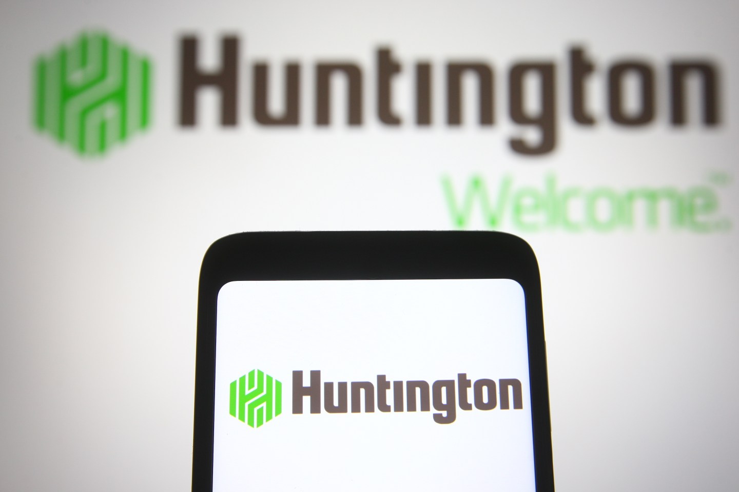 In this photo illustration, the Huntington Bancshares logo of the US bank holding company seen on a smartphone and on a pc screen.