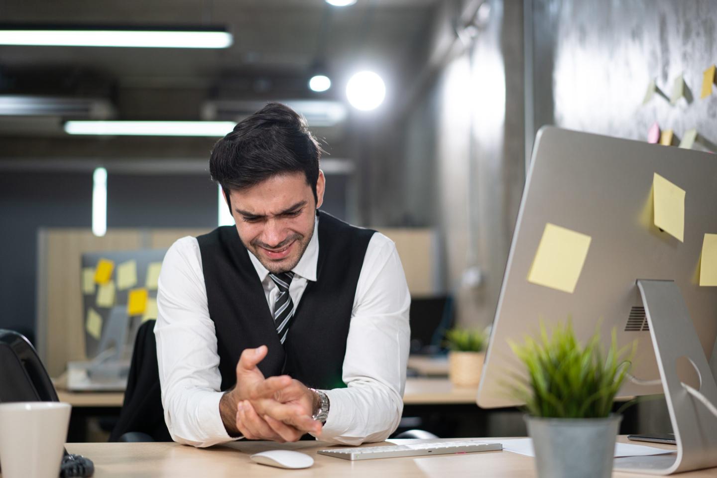 Man sitting at his computer massaging his hands