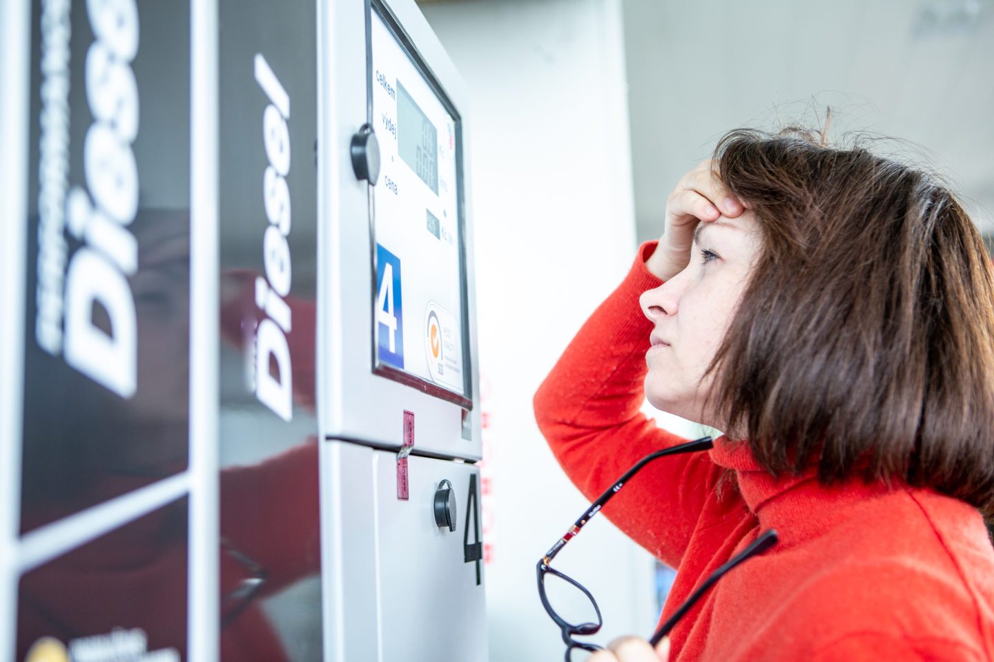 A woman looks concerned as she fills up at a gas station