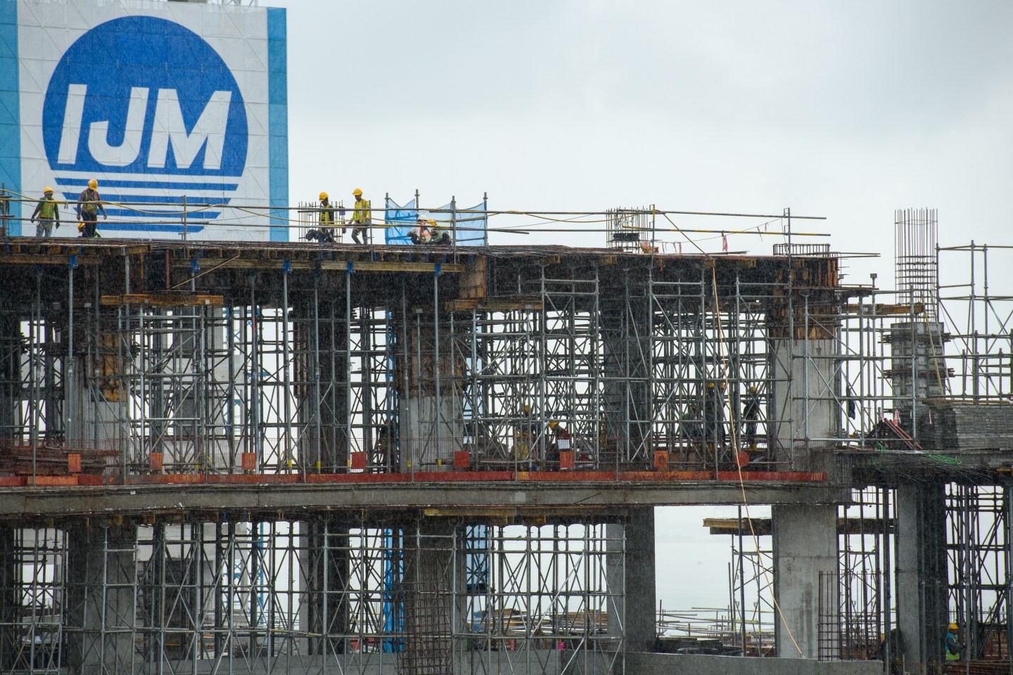 GEORGE TOWN, PENANG, MALAYSIA - 2023 July 19 Workers work under the rain at the The Light City construction sites, The Light City is poised to emerge as one of Penang’s most prominent waterfront destinations
