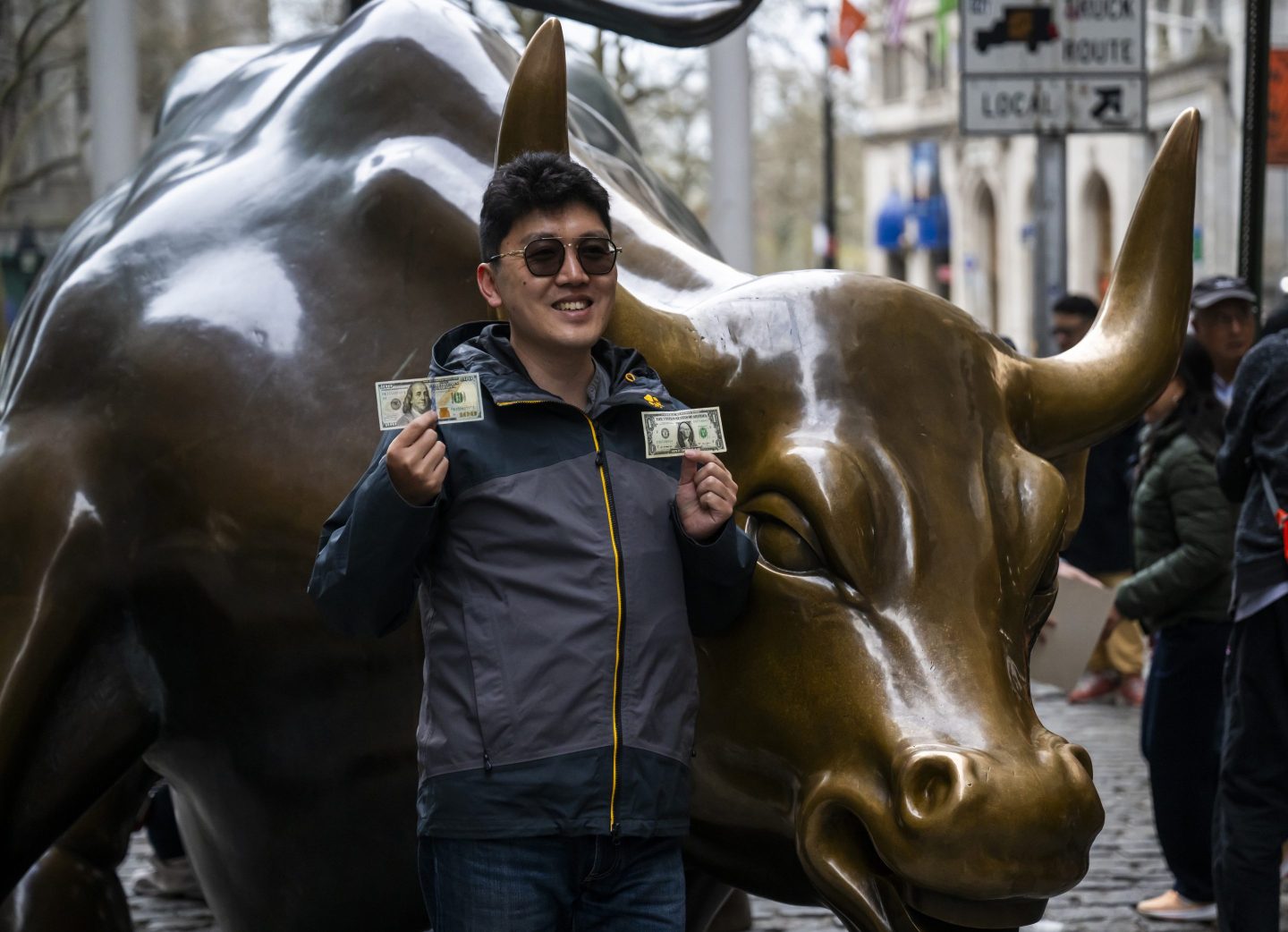 Members of the public pose for photographs beside the Charging Bull, sometimes referred to as the Bull of Wall Street or the Bowling Green Bull on Broadway on April 14, 2025 in New York City.
