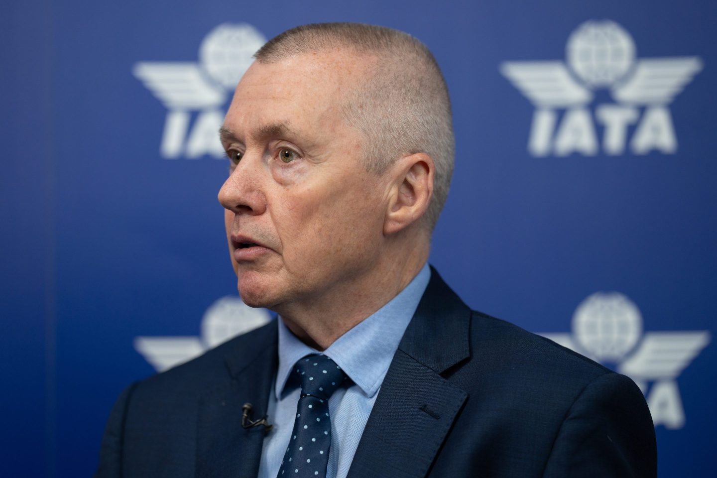 Willie Walsh, wearing a blue suit, looks to his right with his mouth slightly open.