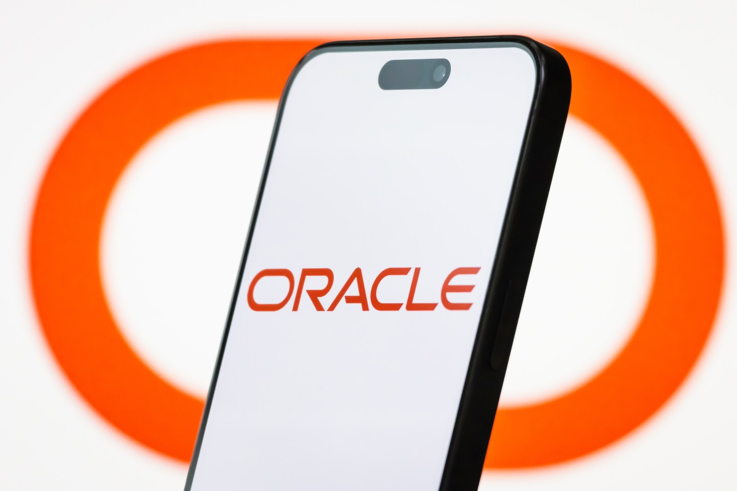 In this photo illustration, the logo of Oracle Corporation is displayed on a smartphone screen, with the company’s signature red branding visible in the background