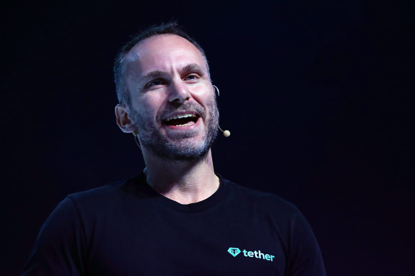 Tether CEO Paolo Ardoino smiles during a speech