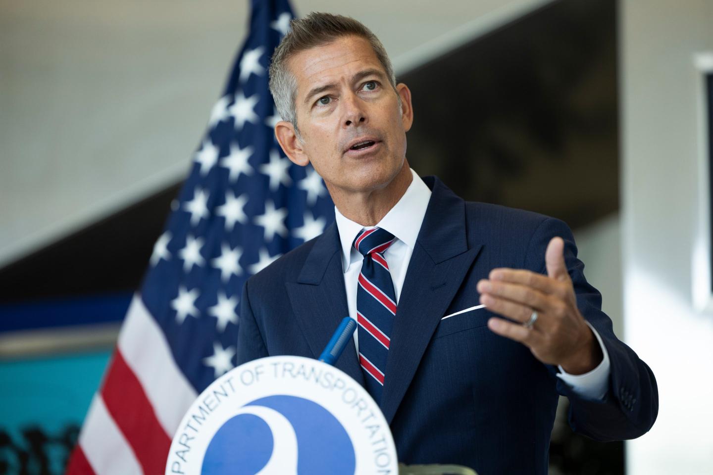 Sean Duffy speaks behind a podium. An American flag hangs behind him.