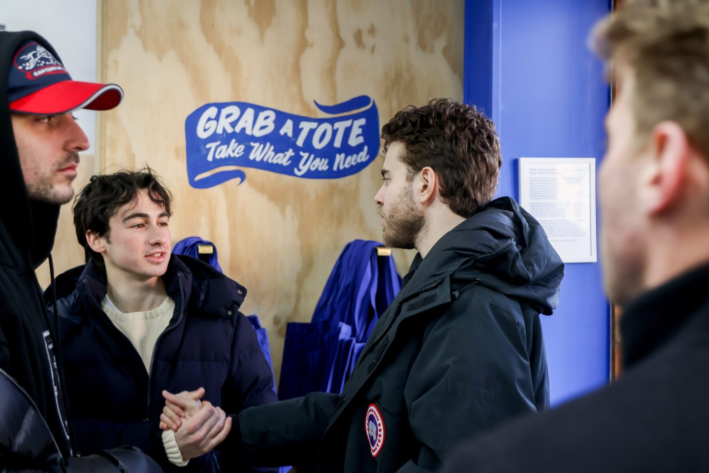 Polymarket CEO Shayne Coplan shakes someone's hand at the opening of Polymarket's temporary free grocery store in Manhattan