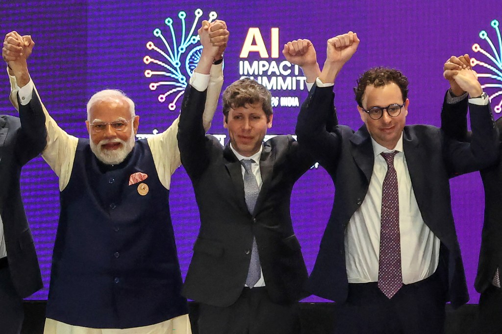 OpenAI CEO Sam Altman (center) and Anthropic CEO Dario Amodei (right), not holding hands, in New Delhi on February 19, 2026. (Photo by Ludovic Marin/AFP/Getty Images)