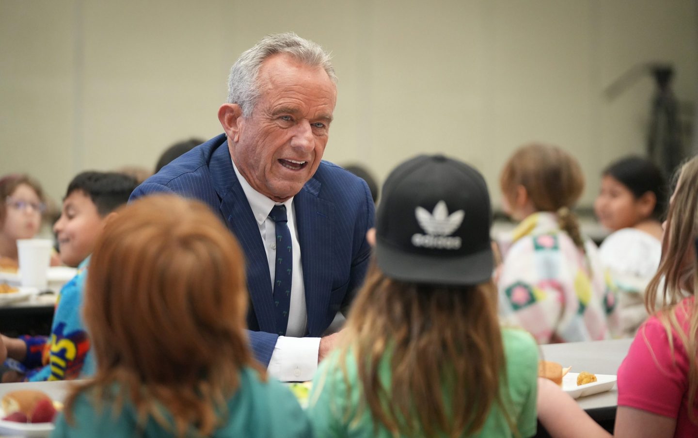 Robert F. Kennedy Jr. sits at a cafeteria table with schoolchildren.