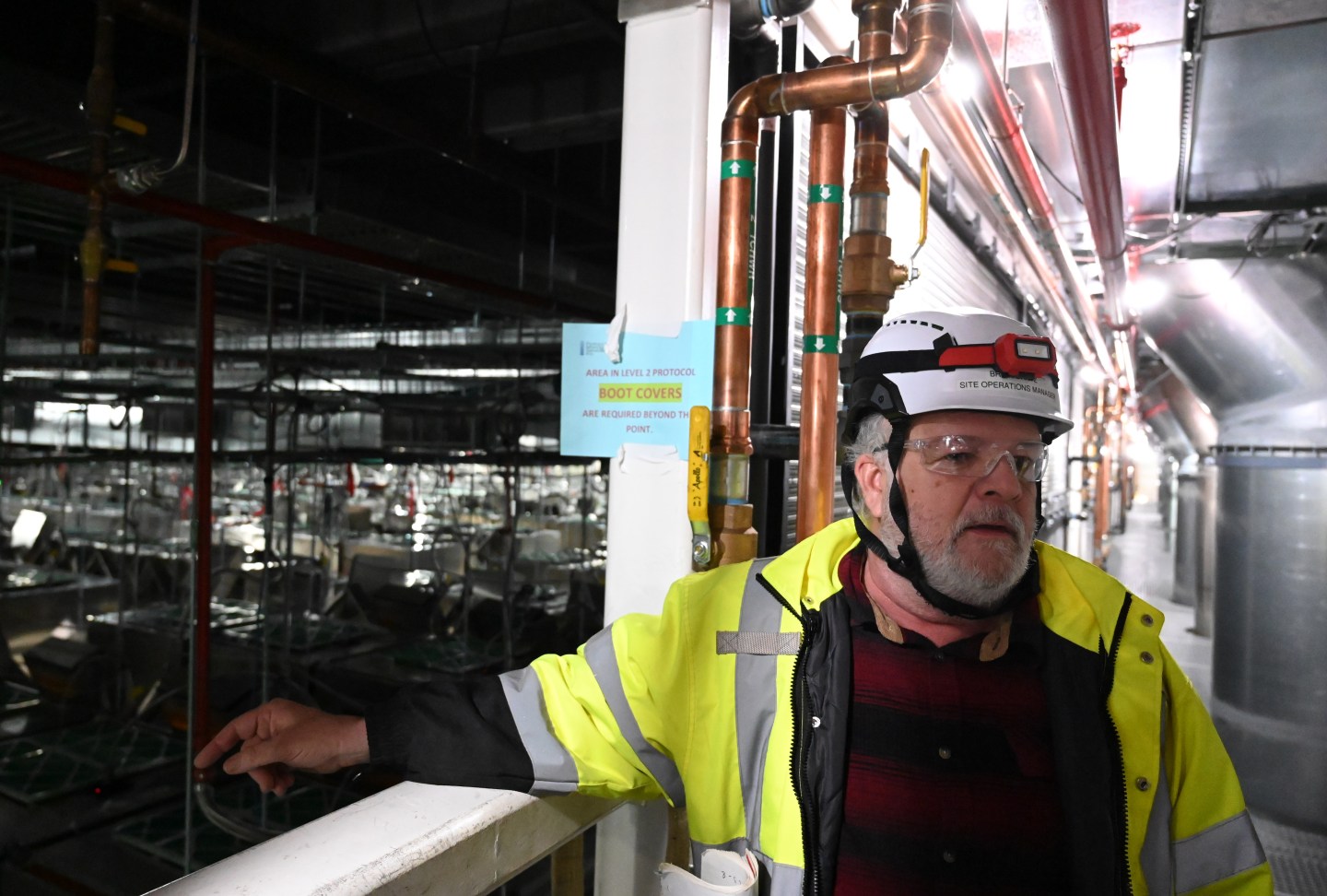 A chip research center site operations manager stands next to a window overlooking the facility.