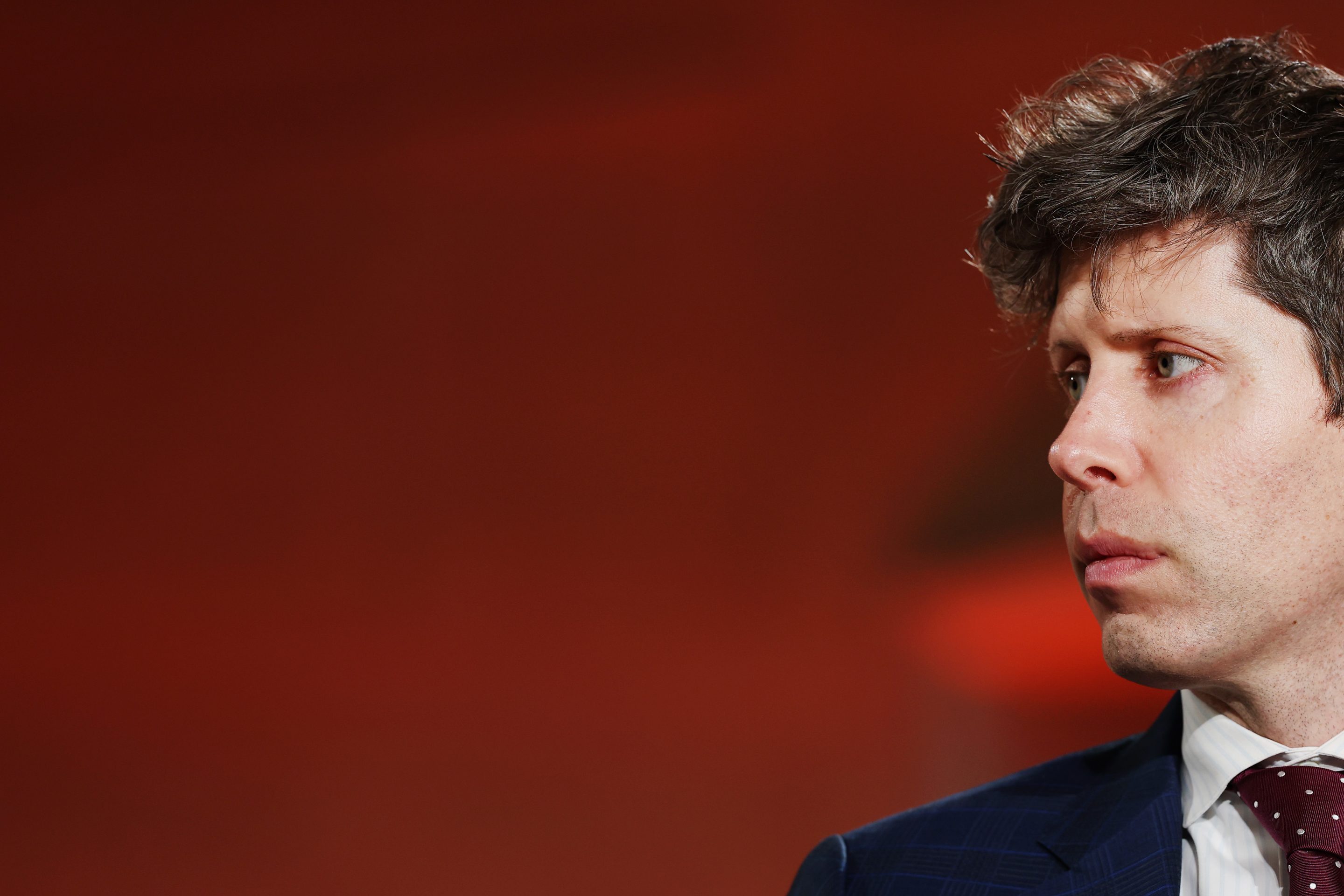 A portrait of OpenAI CEO Sam Altman in profile.