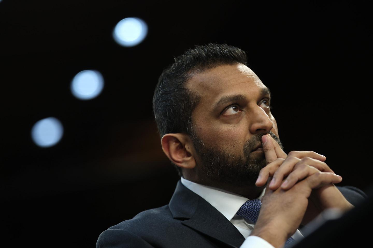 Kash Patel sits with his two fingers on lips
